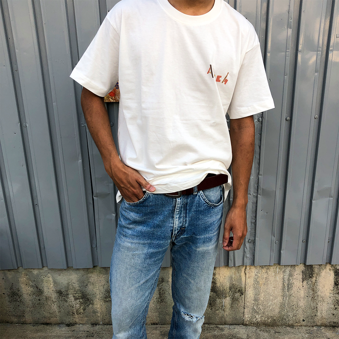 アーチの白いロゴｔシャツを着て立っている人